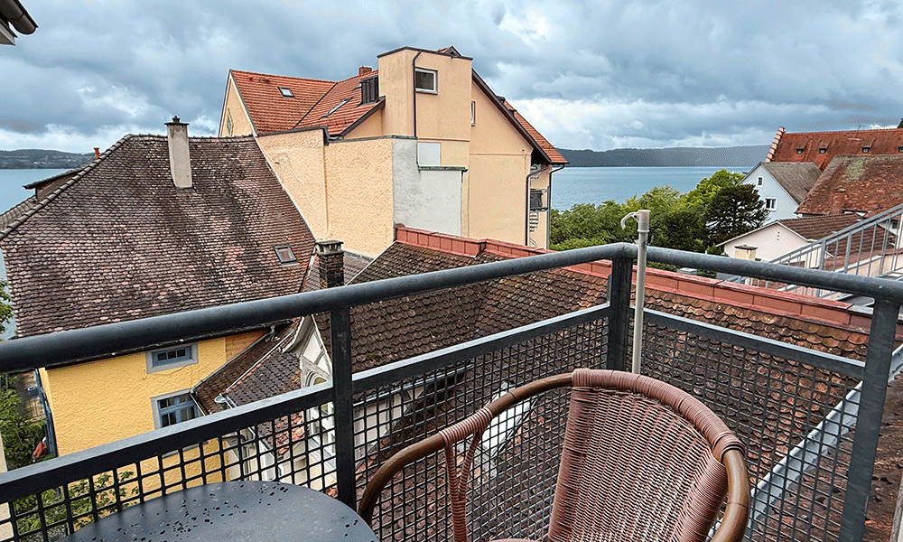 Blick über die Altstadtdächer auf den bewölkten See von Ferienwohnung 1212 aus.