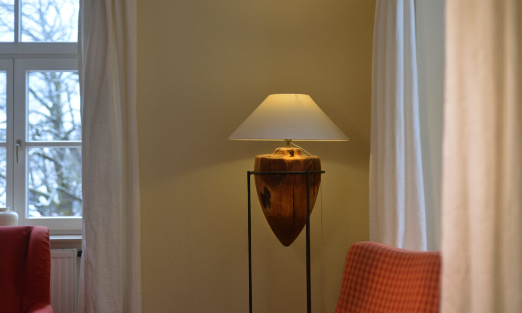 Detail der Ferienwohnung 111 mit aussergewöhnlicher Schirmlampe und roten Sesseln.