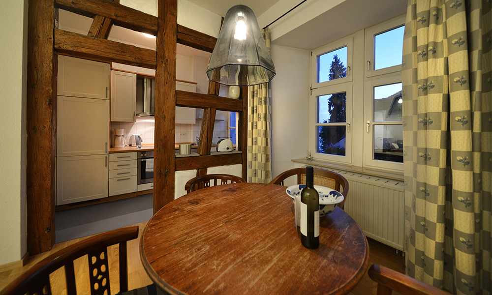 Blick über den Essbereich in die hinter freigelegtem Fachwerk befindliche Küche der Ferienwohnung 777